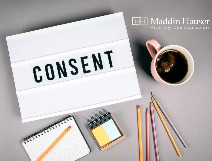 The word consent in a lightbox with pencils and a mug of coffee